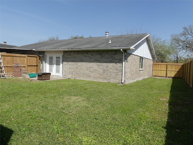 back of property with brick siding, a lawn, french doors, and a fenced backyard