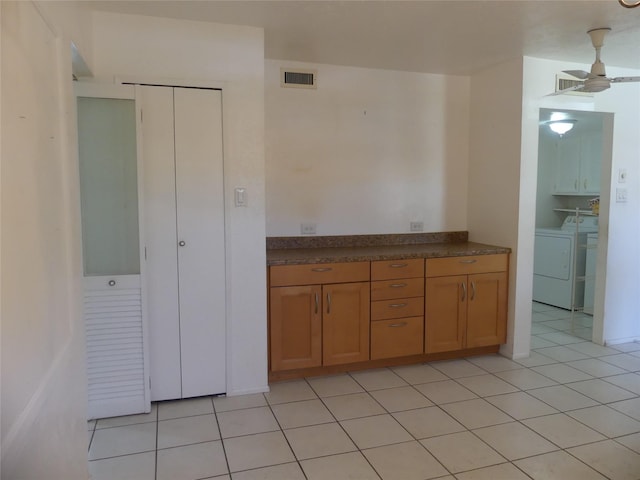 kitchen with dark countertops, light tile patterned floors, visible vents, and brown cabinets