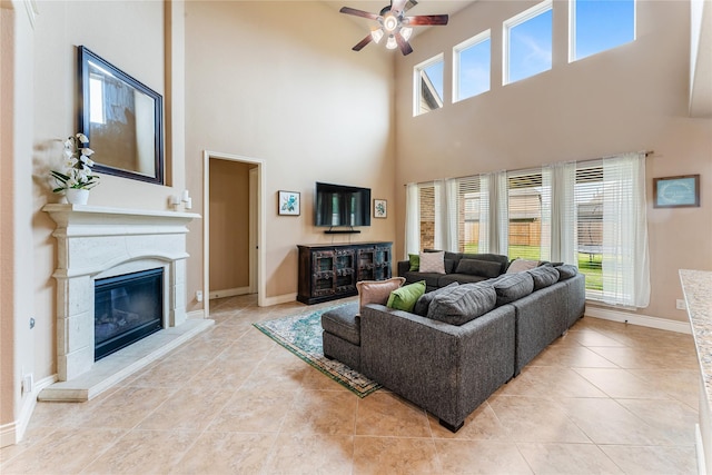 17131 Lumberton Dr, Cypress, TX 77433 - living area with a towering ceiling, a glass covered fireplace, ceiling fan, light tile patterned flooring, and baseboards