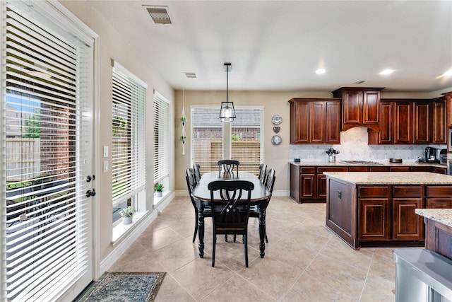 17131 Lumberton Dr, Cypress, TX 77433 - kitchen featuring decorative backsplash, dark brown cabinets, decorative light fixtures, and light tile patterned floors