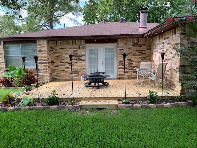 back of house featuring a wooden deck, a shingled roof, french doors, a fire pit, and brick siding