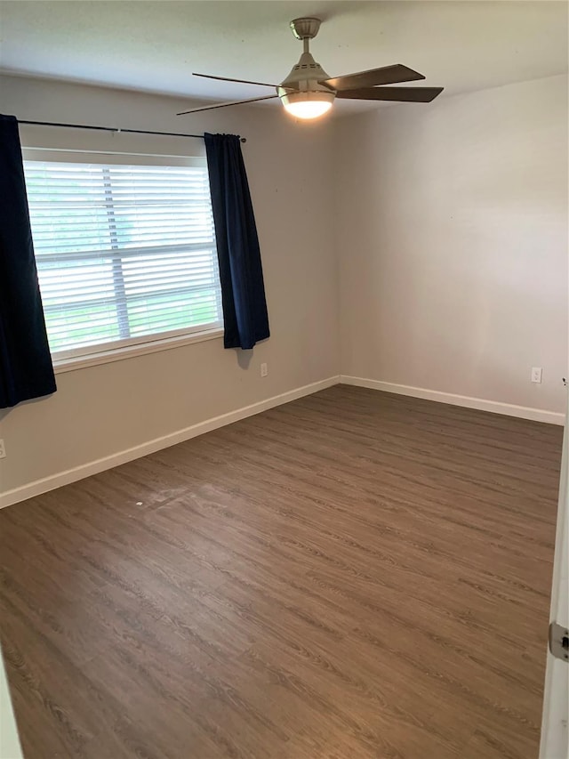 spare room featuring dark wood finished floors, a ceiling fan, and baseboards