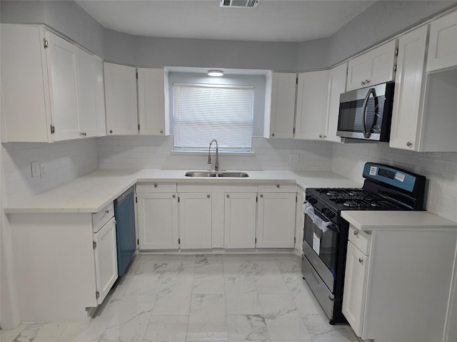 kitchen with stainless steel appliances, light marble finish flooring, a sink, white cabinetry, and backsplash