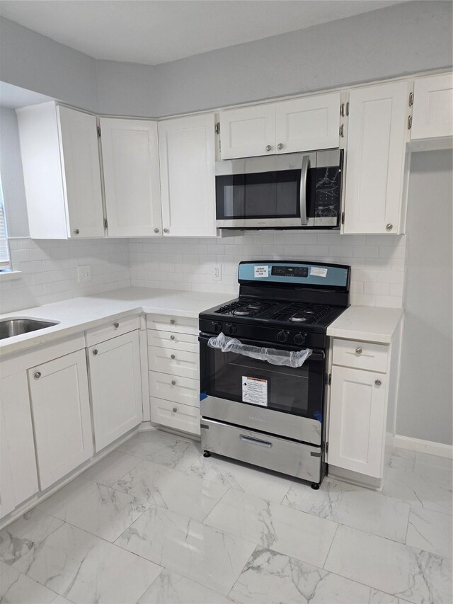 kitchen with stainless steel appliances, light countertops, and white cabinetry