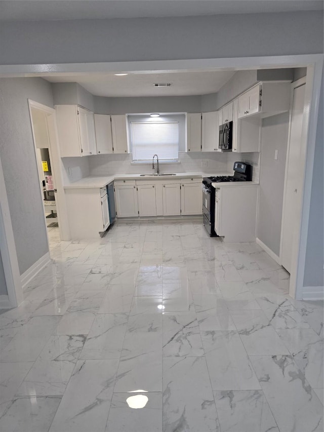 kitchen featuring stainless steel appliances, a sink, baseboards, and white cabinetry