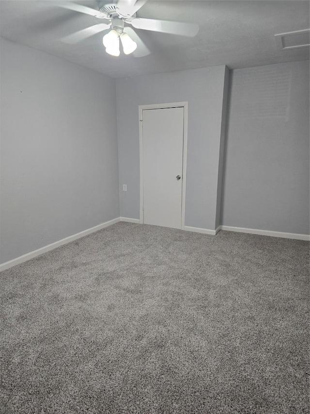 carpeted empty room with ceiling fan and baseboards
