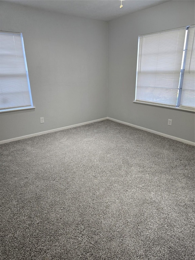 carpeted spare room featuring plenty of natural light and baseboards