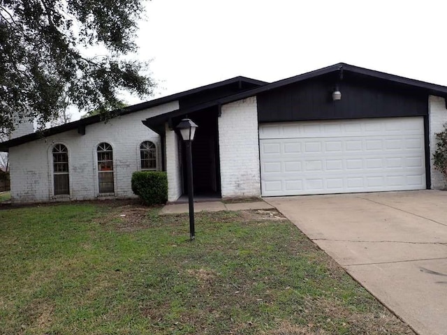 view of front of house with brick siding, driveway, an attached garage, and a front yard