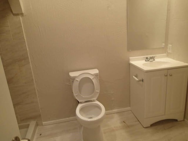 bathroom featuring vanity, toilet, and baseboards