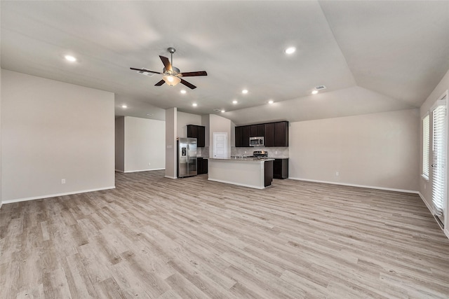 kitchen with open floor plan, light wood-style flooring, appliances with stainless steel finishes, and lofted ceiling