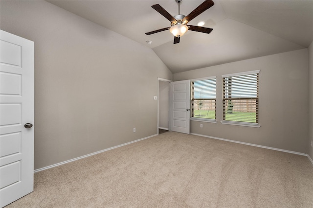 carpeted empty room with baseboards, a ceiling fan, and vaulted ceiling