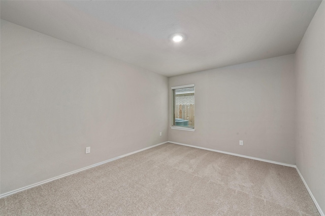 spare room with light colored carpet and baseboards