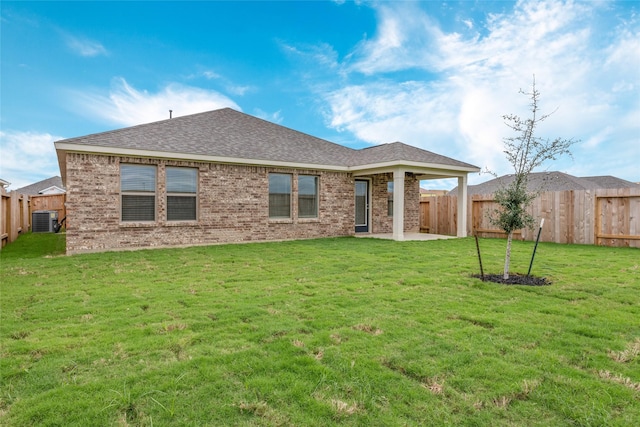 back of property with central AC unit, brick siding, a fenced backyard, and a lawn