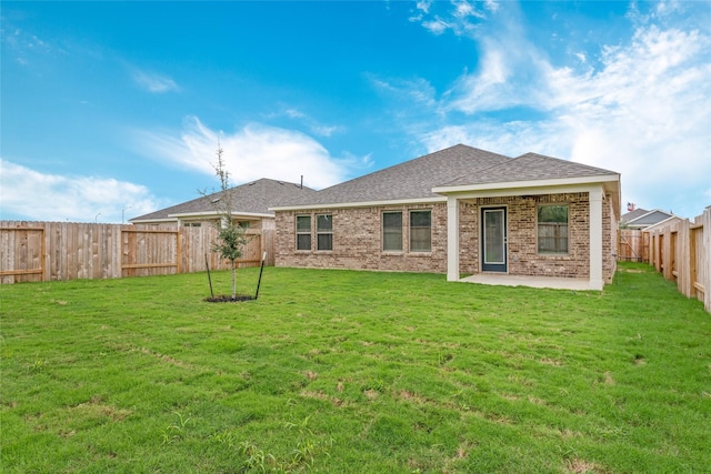 back of house with a patio, a lawn, brick siding, and a fenced backyard