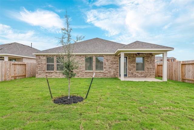 back of property with brick siding, a fenced backyard, and a lawn