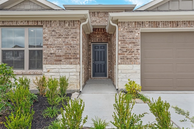 view of exterior entry featuring a garage, brick siding, and stone siding