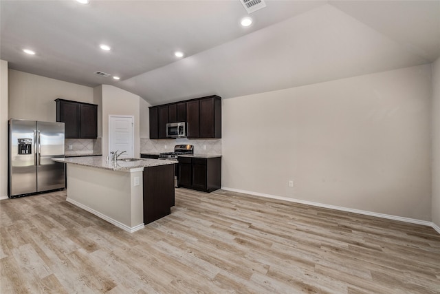 kitchen with decorative backsplash, lofted ceiling, light wood-style floors, and appliances with stainless steel finishes