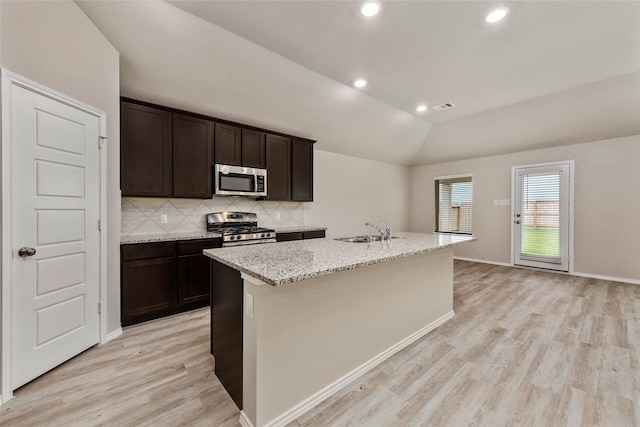 kitchen with visible vents, a kitchen island with sink, a sink, appliances with stainless steel finishes, and vaulted ceiling