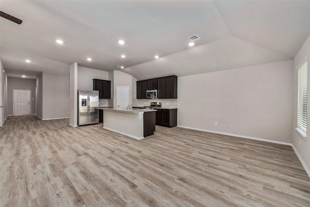 kitchen with stainless steel appliances, lofted ceiling, open floor plan, and light wood finished floors