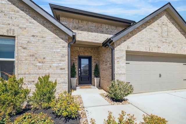 entrance to property featuring concrete driveway, brick siding, and a garage