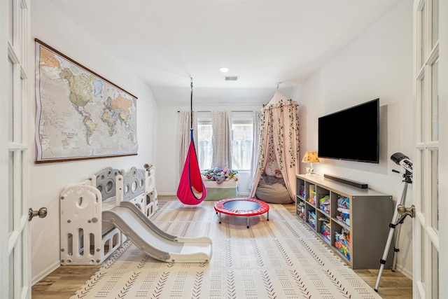 playroom with visible vents, baseboards, and wood finished floors