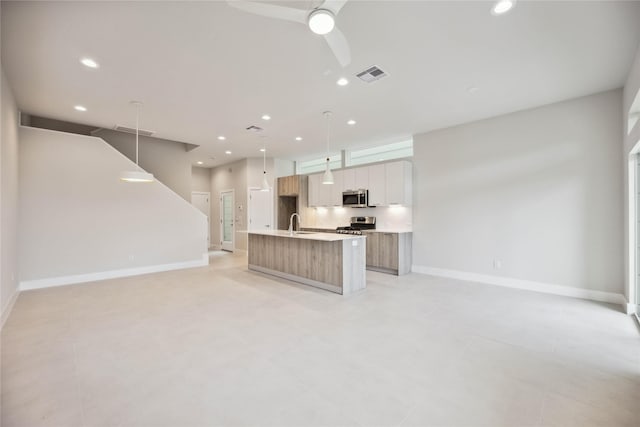 kitchen featuring stainless steel appliances, open floor plan, a center island with sink, visible vents, and recessed lighting
