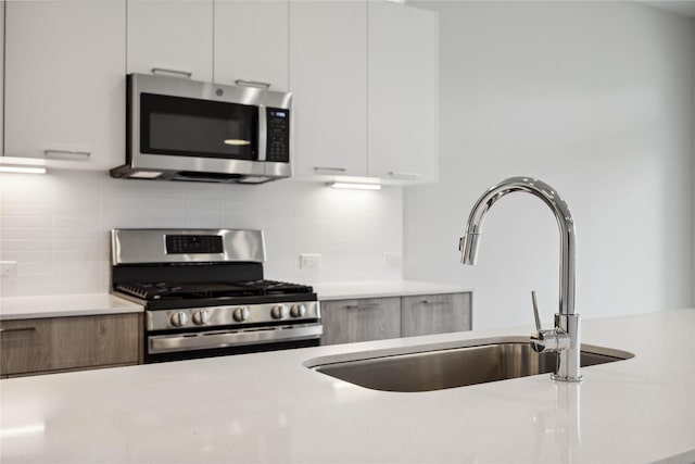 kitchen featuring light countertops, modern cabinets, appliances with stainless steel finishes, and a sink