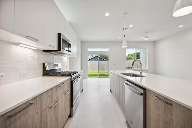kitchen featuring a sink, modern cabinets, light countertops, appliances with stainless steel finishes, and decorative backsplash