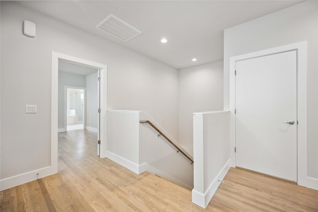 hall featuring wood finished floors, visible vents, an upstairs landing, and recessed lighting