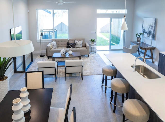 living room with a ceiling fan, baseboards, and plenty of natural light