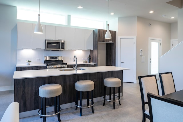 kitchen featuring stainless steel appliances, tasteful backsplash, a sink, and white cabinets
