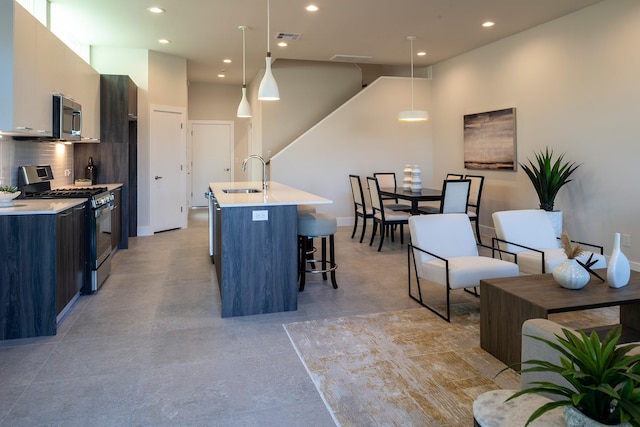 kitchen with a kitchen bar, a sink, modern cabinets, appliances with stainless steel finishes, and recessed lighting