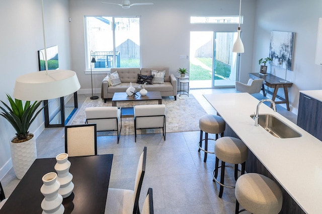 living area with baseboards, a healthy amount of sunlight, and ceiling fan