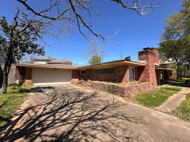 view of front facade with a garage, brick siding, a chimney, and concrete driveway