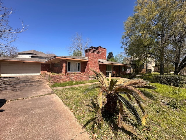 view of front of house with concrete driveway, brick siding, a garage, and a chimney