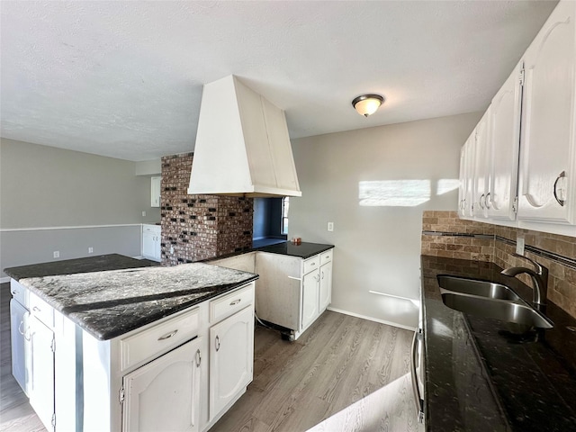 kitchen featuring decorative backsplash, light wood-style flooring, white cabinetry, and a sink