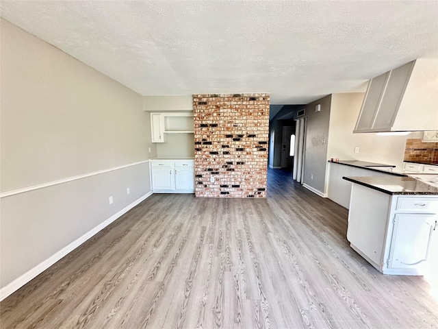 interior space featuring a textured ceiling, dark countertops, and light wood finished floors