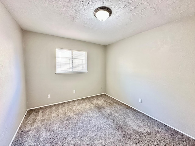 spare room featuring a textured ceiling, baseboards, and carpet floors