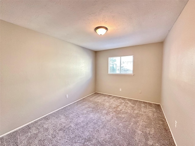 spare room with a textured ceiling, baseboards, and carpet floors