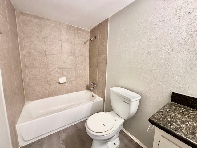 full bath with baseboards, toilet, wood finished floors, a textured wall, and washtub / shower combination