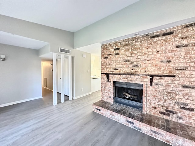 unfurnished living room featuring a fireplace, wood finished floors, visible vents, and baseboards