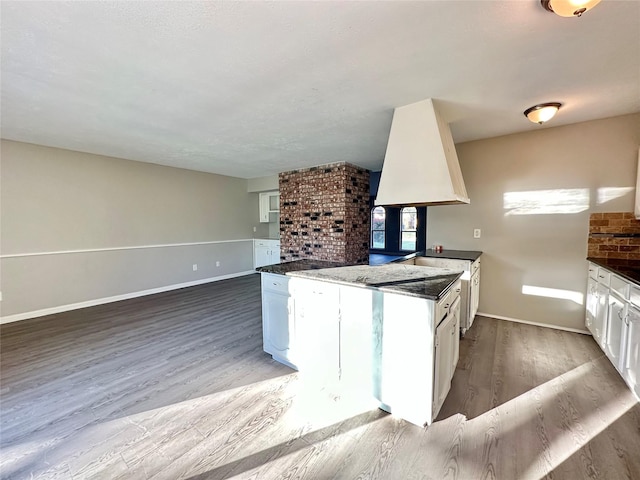 kitchen with white cabinetry, open floor plan, wood finished floors, and baseboards