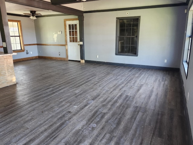 unfurnished living room featuring dark wood-style floors, baseboards, crown molding, and ceiling fan