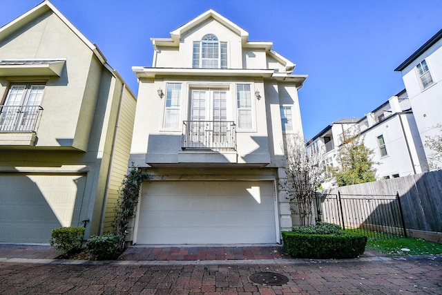 view of front of home with an attached garage, fence, and stucco siding