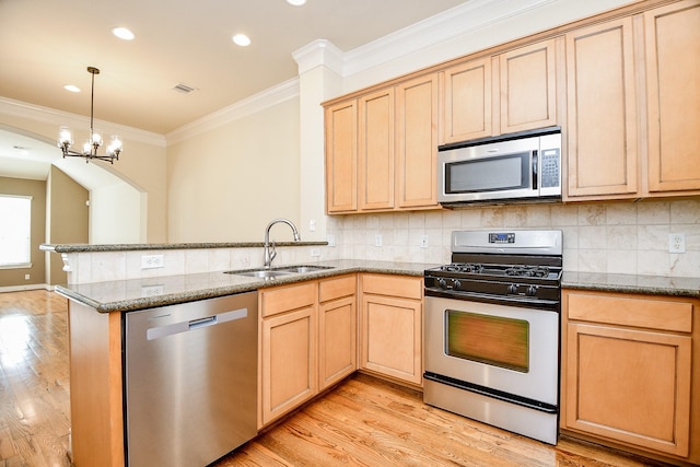 kitchen with light brown cabinets, decorative backsplash, appliances with stainless steel finishes, and a sink