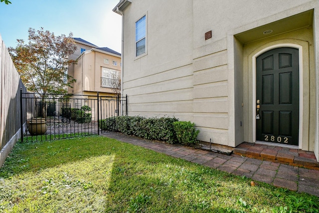 doorway to property with a lawn and fence