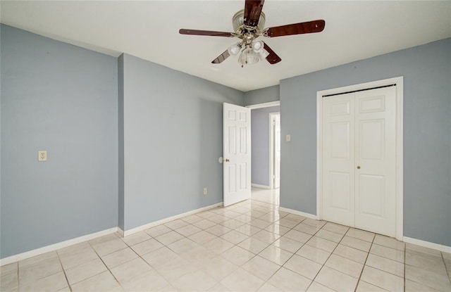 unfurnished bedroom with light tile patterned floors, baseboards, a closet, and ceiling fan