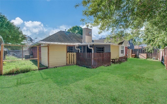 back of property with a lawn, roof with shingles, a fenced backyard, and a chimney