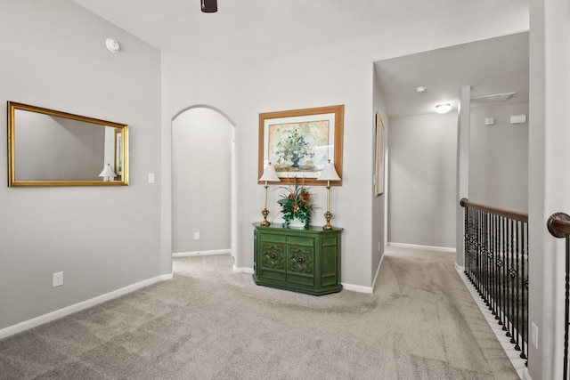 hall featuring baseboards, carpet flooring, and arched walkways