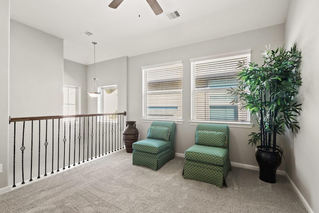 living area featuring ceiling fan, carpet floors, visible vents, and baseboards